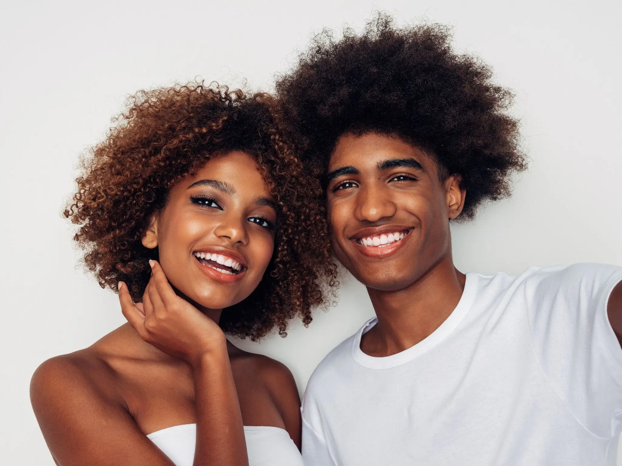Smiling couple with curly hair posing together.