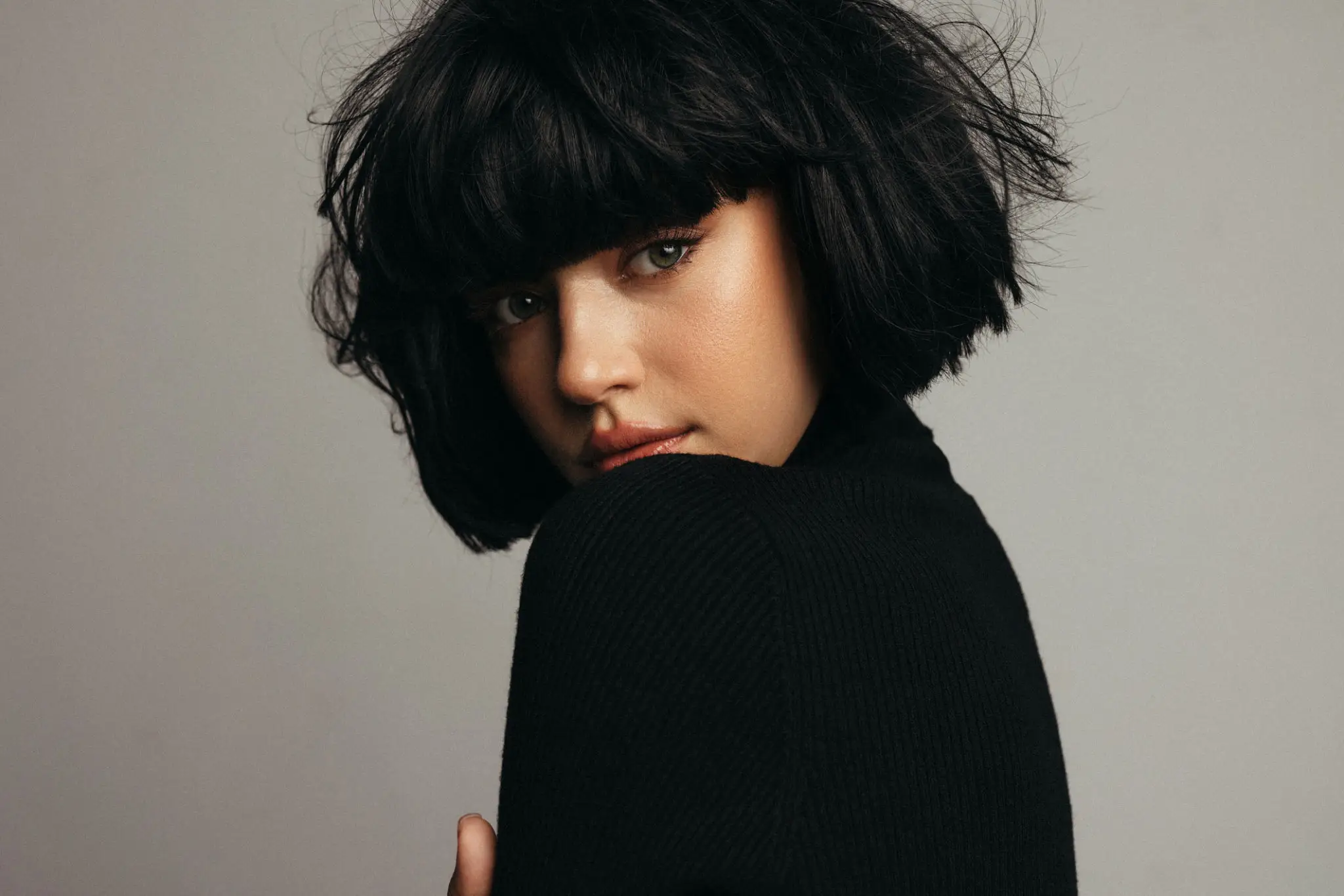 Woman with short black hair, looking back.