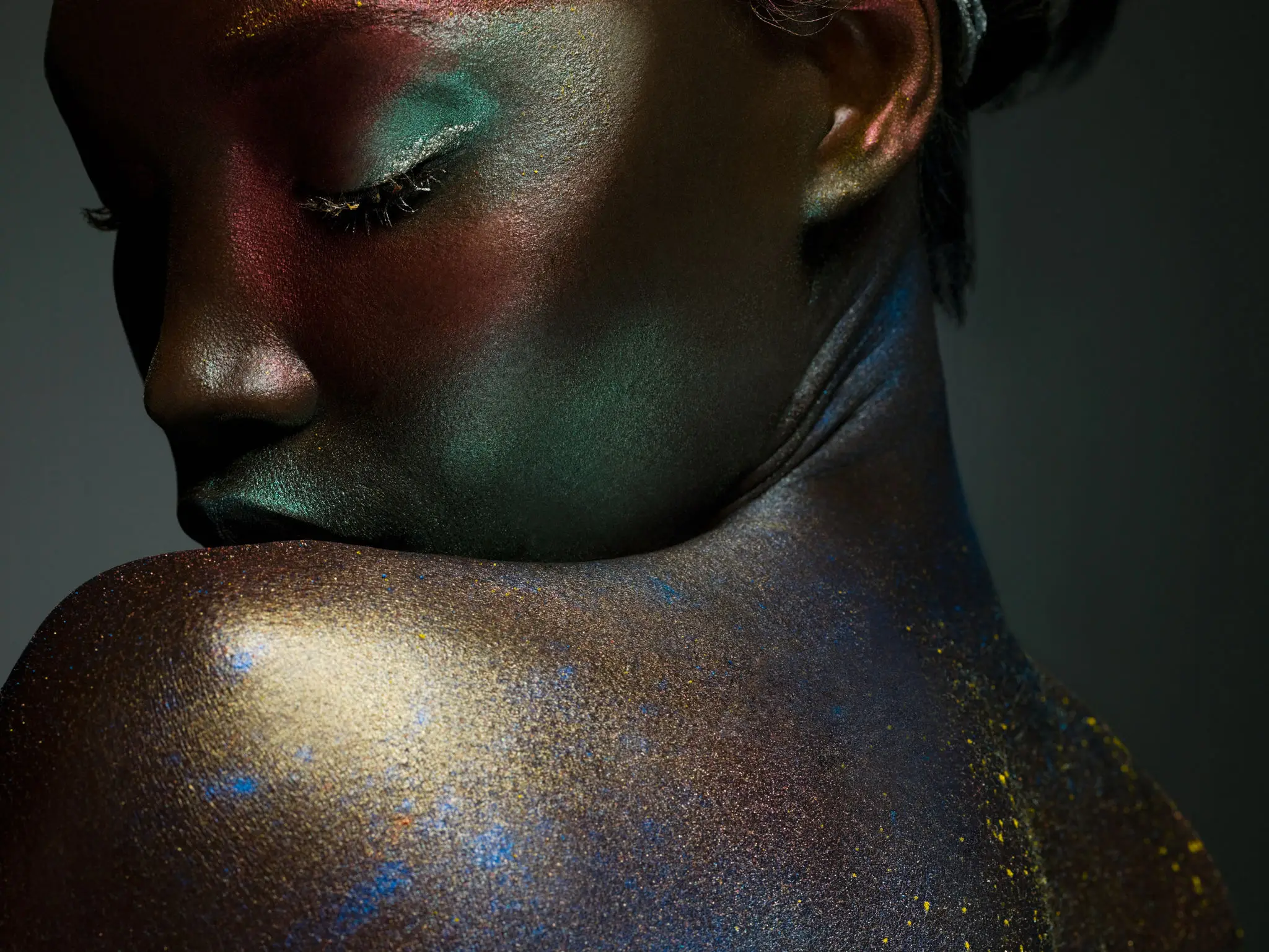 Colorful glitter makeup on woman's shoulder.
