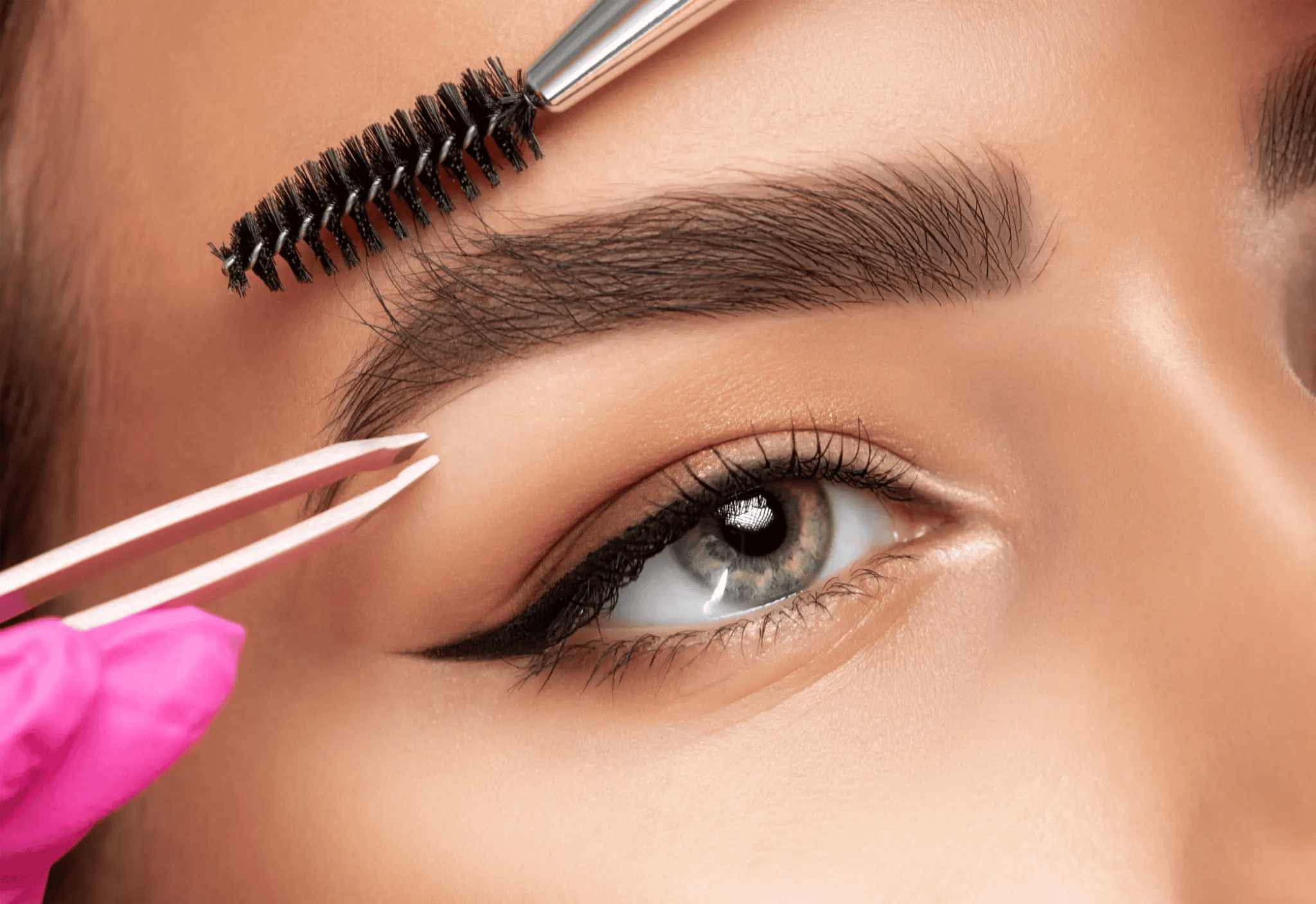 Eyebrow grooming with tweezers and brush.