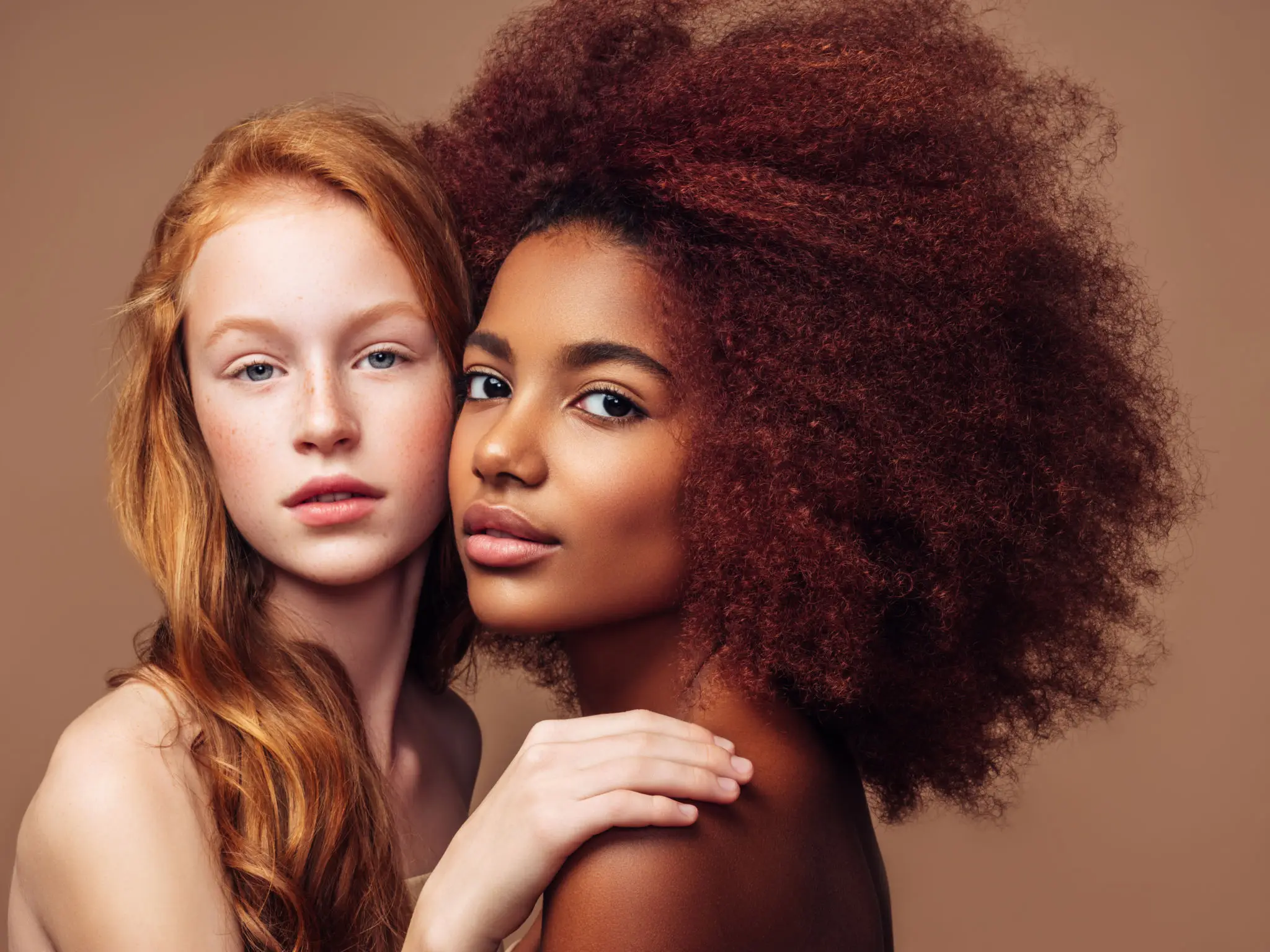 Two women with diverse hairstyles embracing.