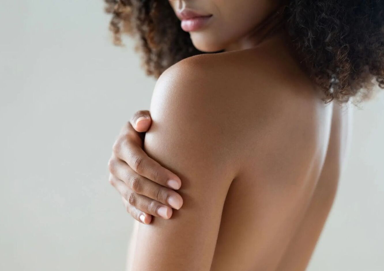 Person touching their bare shoulder gently.