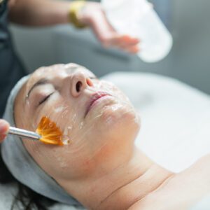 Woman receiving facial treatment with brush.