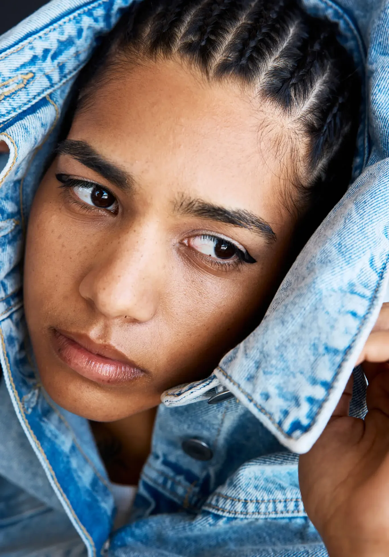 Person with braided hair in denim jacket.