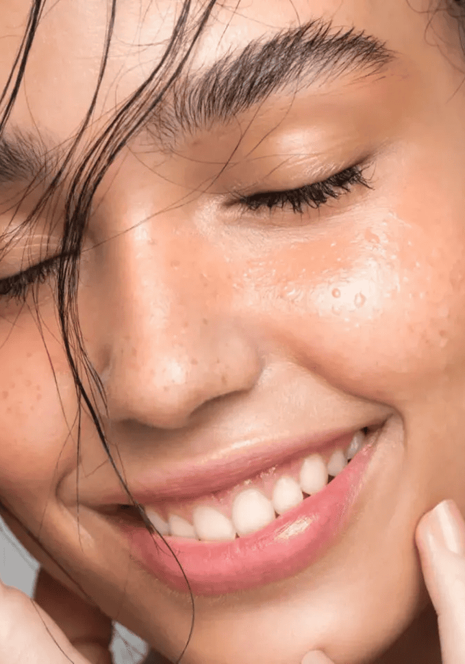 Smiling woman with glowing, freckled skin.